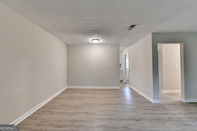 spare room with light wood-style floors, baseboards, and visible vents