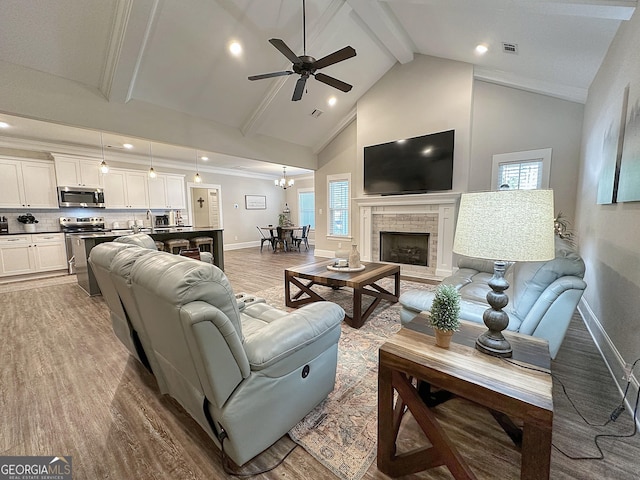 living area with wood finished floors, visible vents, baseboards, ceiling fan, and beamed ceiling