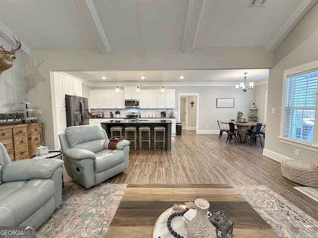 living room with crown molding, a notable chandelier, light wood finished floors, and beam ceiling