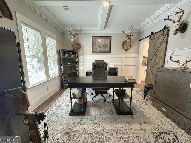 office area with a barn door, visible vents, a decorative wall, crown molding, and wood finished floors
