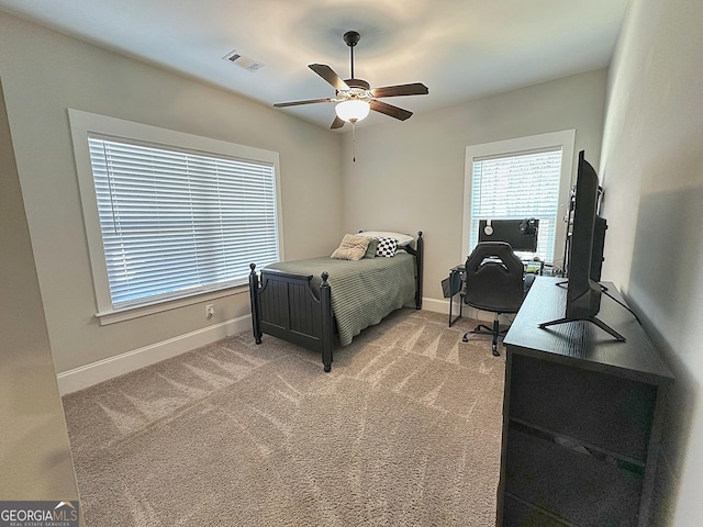 bedroom featuring light colored carpet, visible vents, baseboards, and ceiling fan