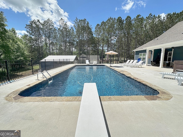 view of swimming pool with a patio area, a diving board, a fenced in pool, and fence