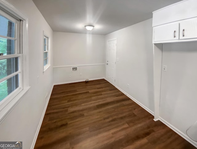 unfurnished dining area featuring baseboards and dark wood finished floors