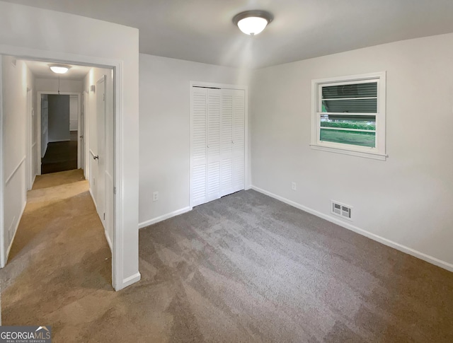 unfurnished bedroom featuring carpet flooring, attic access, baseboards, visible vents, and a closet
