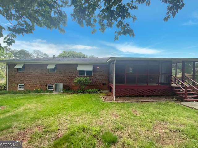 rear view of property featuring a sunroom, a yard, and brick siding