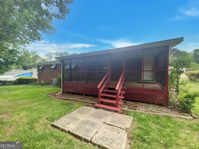 rear view of property featuring a lawn and a sunroom