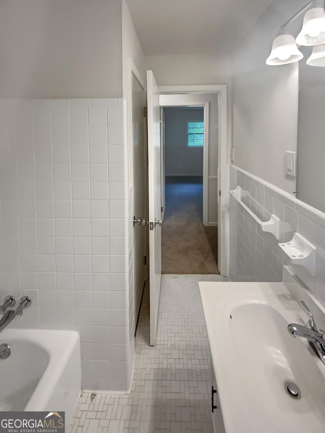 bathroom with vanity, wainscoting, tile walls, a tub, and tile patterned floors