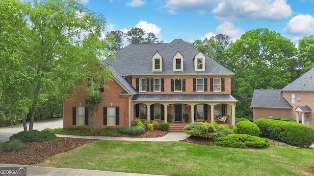 view of front of property featuring brick siding, covered porch, and a front yard