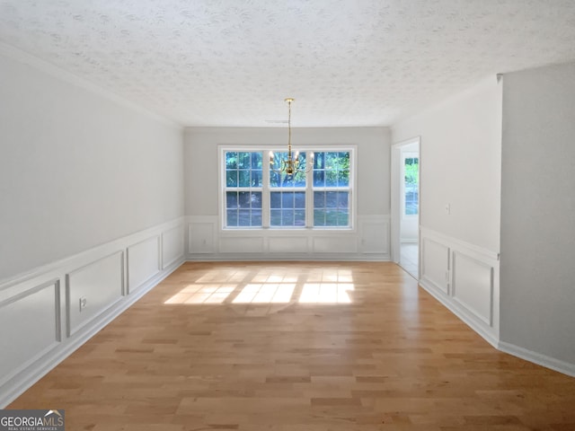 30 Trelawney Ct, Covington, GA 30016 - unfurnished dining area with an inviting chandelier, wainscoting, light wood-style flooring, and a decorative wall