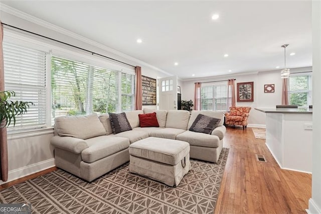 living area with baseboards, ornamental molding, light wood-style flooring, and recessed lighting