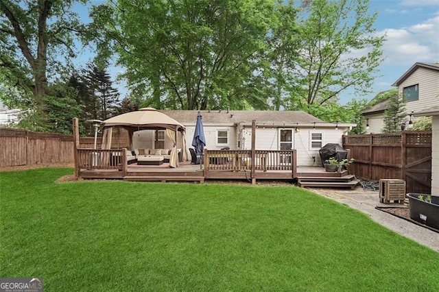 back of house featuring a deck, a gazebo, a fenced backyard, a yard, and outdoor lounge area