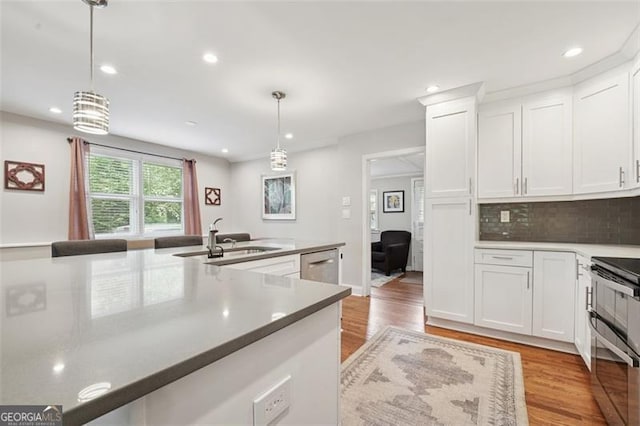kitchen with a sink, white cabinets, light wood-type flooring, and double oven range