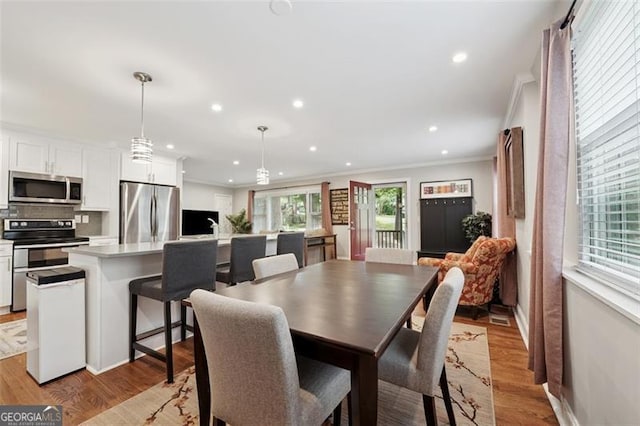 dining area with crown molding, recessed lighting, light wood finished floors, and baseboards