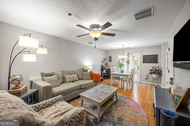 268 Cottonwood Creek Cir, Canton, GA 30114 - living room featuring a textured ceiling, visible vents, ceiling fan with notable chandelier, and light wood-type flooring
