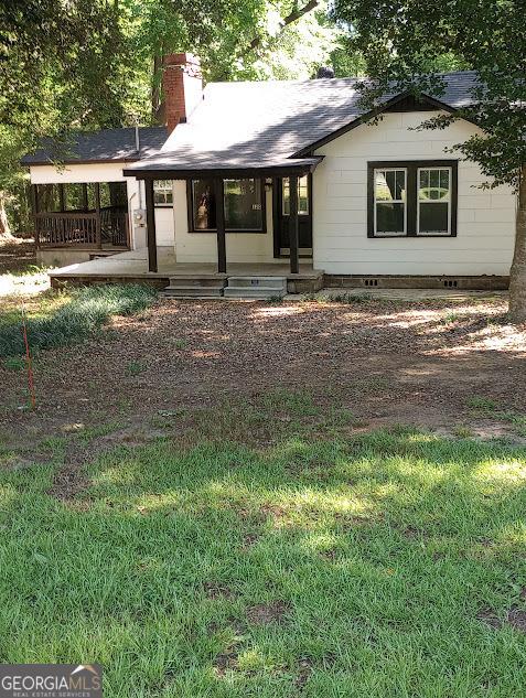 back of property with crawl space, covered porch, and a chimney