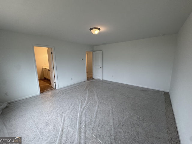unfurnished bedroom featuring carpet floors, baseboards, and ensuite bath