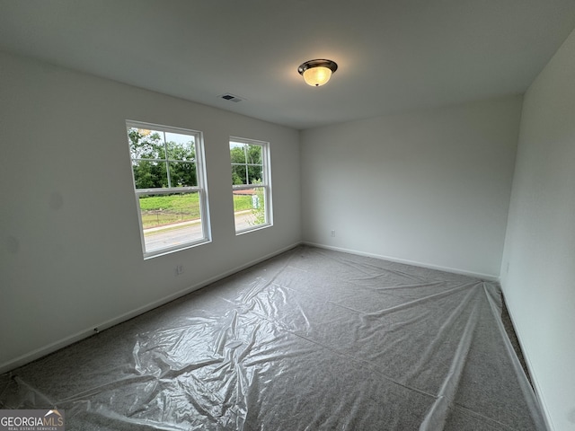 carpeted empty room featuring baseboards and visible vents
