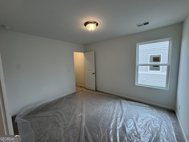 spare room featuring carpet floors, baseboards, and visible vents