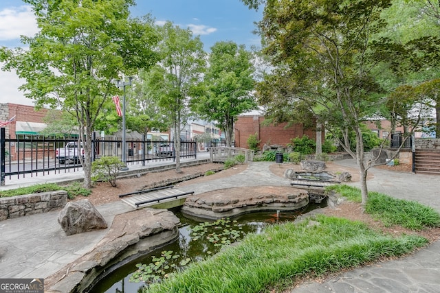 surrounding community featuring fence and a small pond