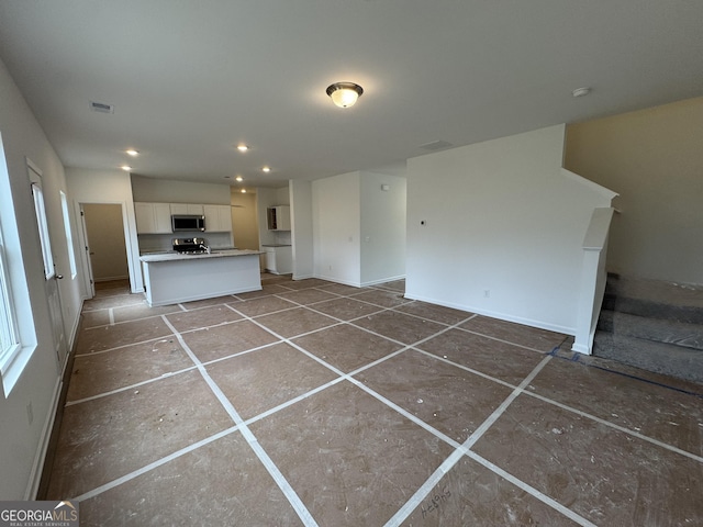 unfurnished living room with baseboards, recessed lighting, stairs, and visible vents