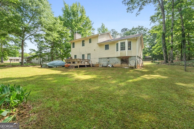 rear view of property with a wooden deck, a chimney, and a yard
