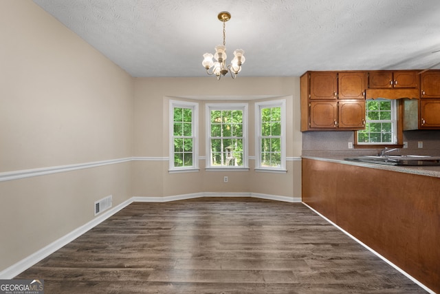 kitchen featuring an inviting chandelier, brown cabinetry, decorative light fixtures, visible vents, and dark wood-style floors