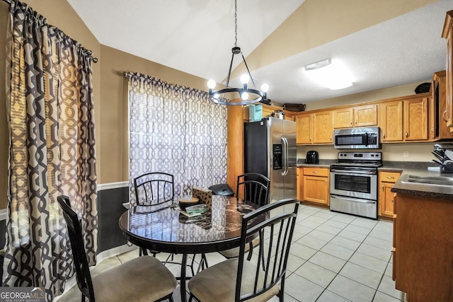 kitchen featuring dark countertops, lofted ceiling, a sink, a notable chandelier, and stainless steel appliances
