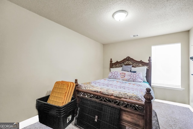 carpeted bedroom featuring baseboards, a textured ceiling, and visible vents