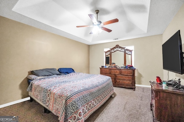bedroom featuring carpet flooring, ceiling fan, a raised ceiling, baseboards, and visible vents