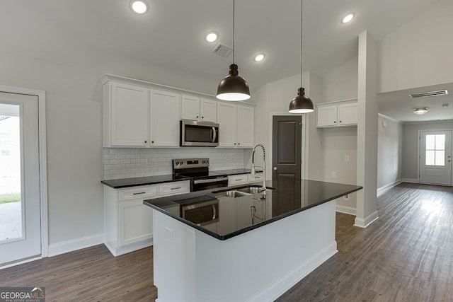kitchen with visible vents, dark countertops, tasteful backsplash, a sink, and stainless steel appliances