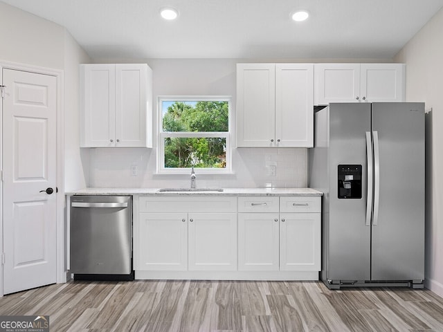 kitchen featuring white cabinets, backsplash, appliances with stainless steel finishes, and a sink