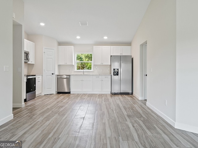 kitchen with baseboards, light wood-style flooring, appliances with stainless steel finishes, and white cabinetry