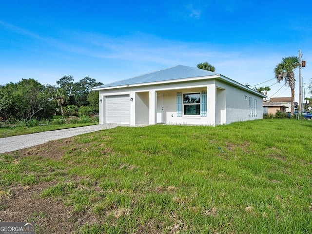 view of front of house with driveway, metal roof, a garage, a front lawn, and stucco siding