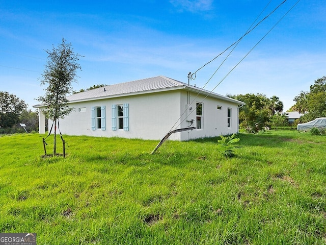 back of property featuring a lawn and stucco siding