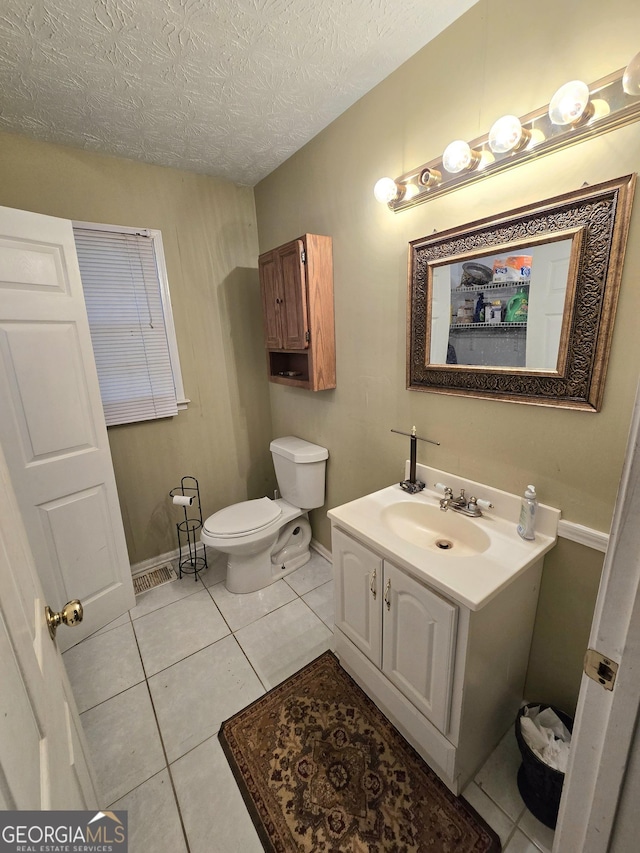 bathroom with tile patterned flooring, vanity, toilet, baseboards, and a textured ceiling