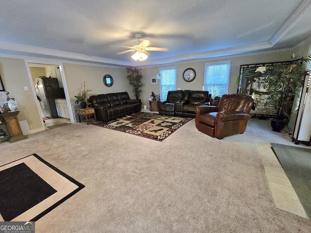 living room featuring a raised ceiling, ornamental molding, carpet flooring, and ceiling fan