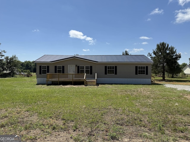 manufactured / mobile home with a wooden deck, metal roof, and a front lawn