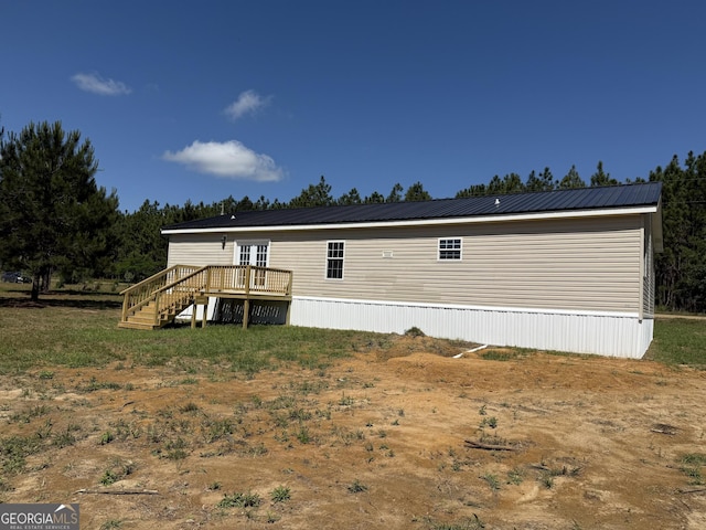 back of property featuring stairway, a deck, and metal roof