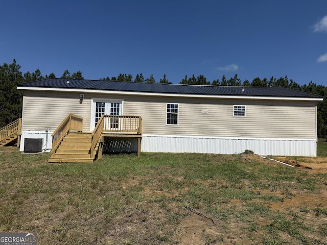 rear view of house featuring a lawn, metal roof, a wooden deck, and stairs