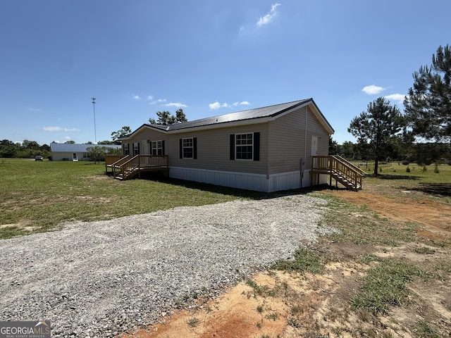 view of front of house with stairs, a front lawn, and gravel driveway