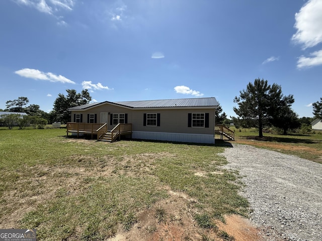 manufactured / mobile home with stairway, a deck, metal roof, and a front lawn