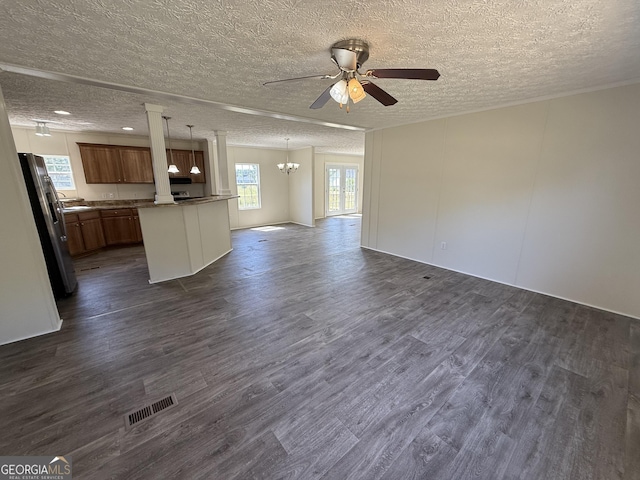unfurnished living room featuring dark wood-style flooring, a textured ceiling, visible vents, and ceiling fan with notable chandelier