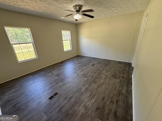 empty room with ceiling fan, dark wood finished floors, a textured ceiling, and visible vents