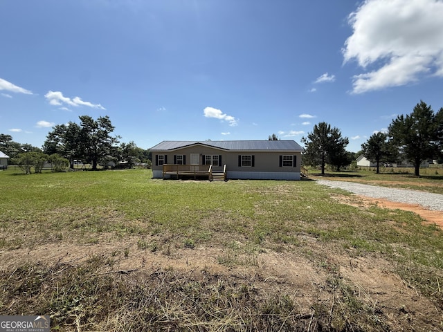 view of front of house featuring driveway, a wooden deck, metal roof, and a front yard