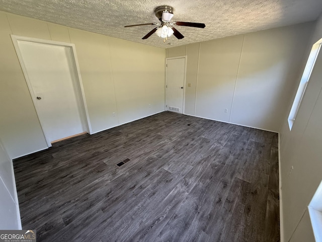 unfurnished bedroom featuring a ceiling fan, a textured ceiling, visible vents, and dark wood-style floors