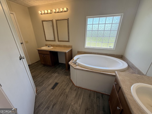 full bath with visible vents, two vanities, a sink, and wood finished floors