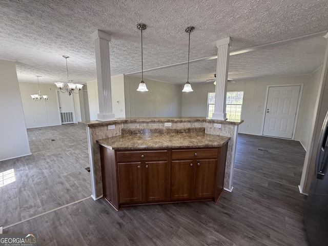 kitchen with an inviting chandelier, dark wood finished floors, open floor plan, decorative columns, and pendant lighting