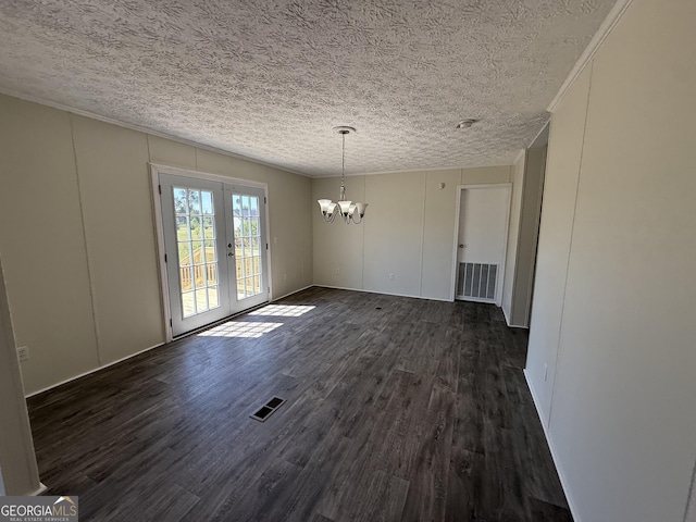 unfurnished dining area featuring a notable chandelier, a textured ceiling, dark wood finished floors, and visible vents