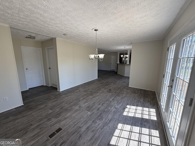 interior space with an inviting chandelier, a textured ceiling, plenty of natural light, dark wood-type flooring, and visible vents