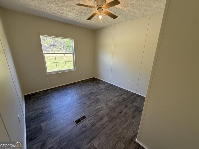 spare room with ceiling fan, dark wood-style floors, a textured ceiling, and visible vents